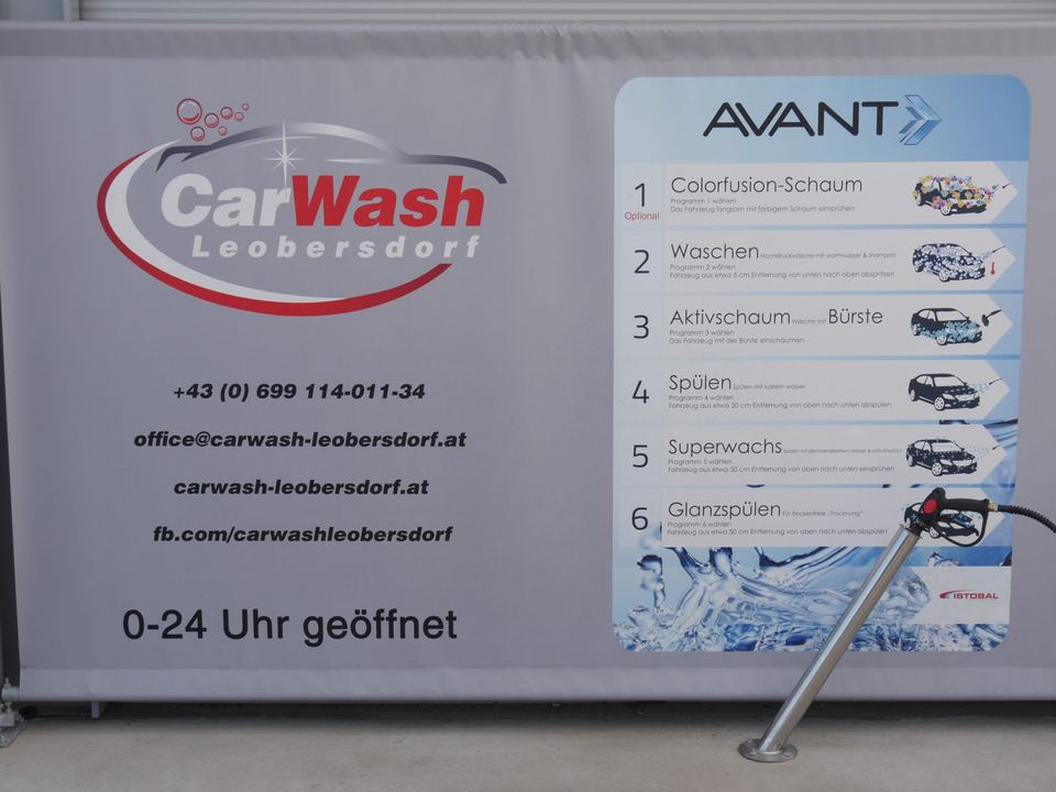 Programmtafel in der Waschbox mit Logo, Kontaktdaten, dem Hinweis „0–24 Uhr geöffnet“ und den Waschprogrammen 1 bis 6